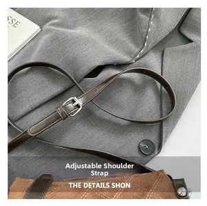 Detail of adjustable dark brown leather strap with silver buckle on a textured handbag