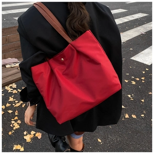 Outdoor shot of large red canvas tote bag with leather strap and golden magnetic clasp