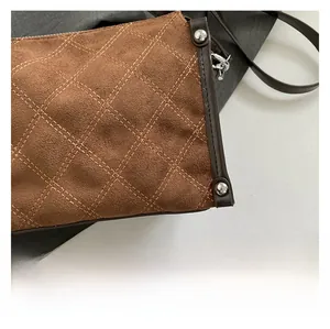 Macro detail of quilted brown suede shoulder bag with silver studs and metal lobster clasp