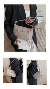 Détail du sac demi-lune en daim kaki avec œillets argentés et bandoulière en cuir souple