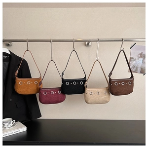 Close-up of five suede underarm bags in various colors hanging on a display rack