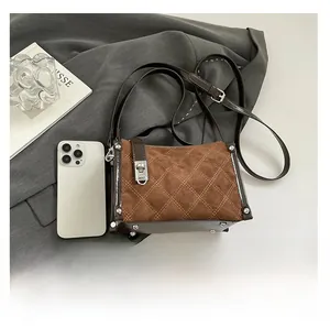 Close-up of vintage brown quilted crossbody bag with metal lock on a grey suit jacket