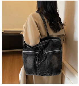 Detailed view of the washed black denim tote bag with silver zippers and long tassels