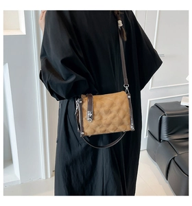 Close-up of brown quilted crossbody bag with metal lock worn on a black dress