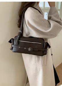 Close-up of dark brown underarm bag featuring silver metal eyelets and adjustable buckle strap