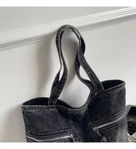 Close-up of black washed denim tote bag with metal zipper and reinforced stitching
