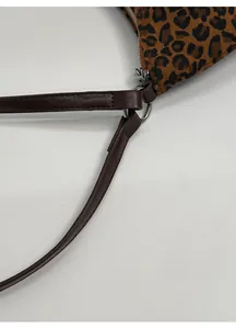 Dettaglio borsa leopardata con tracolla in pelle marrone e fibbia in metallo