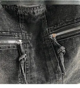 Detail of washed black denim tote bag with metal zippers and textured stitching