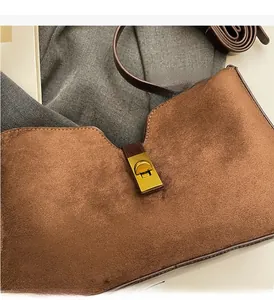 Gros plan du sac en daim marron avec fermoir rotatif doré et bandoulière en cuir