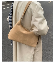 Detail of tan suede hobo bag worn with a trench coat for an autumn street style look