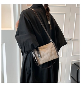 Detail of quilted beige crossbody bag with silver twist lock and dark brown trim