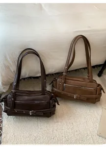 Close-up of vintage brown shoulder bags with buckle straps and metal zippers on a rug