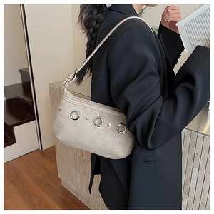 Detail of suede crossbody bag with silver metal rings and rivets on a blazer model