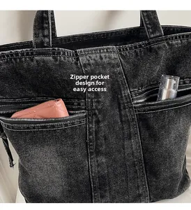 Detail of dual zipper pockets on black denim tote bag with contrast stitching