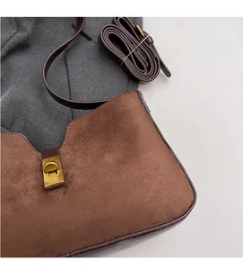 Détail de la texture en daim marron et du fermoir doré vintage sur le sac à main