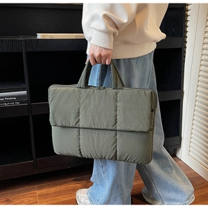 Quilted olive green laptop tote bag with padded finish shown in a stylish lifestyle setting