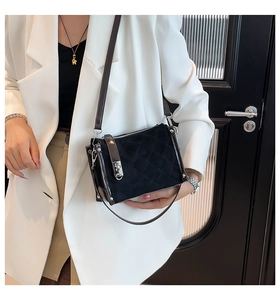 Close-up of black quilted crossbody bag with silver twist lock and leather strap