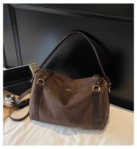 Détail du sac Boston en daim marron foncé avec fermetures éclair dorées et finitions chic