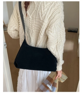 Detail view of a matte black shoulder bag paired with an autumn knit sweater