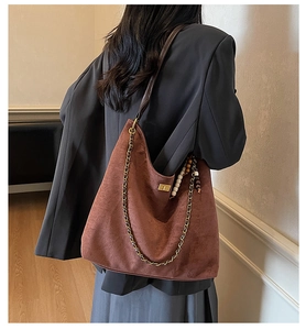 Détail du sac cabas en daim marron rouge avec chaîne en métal et breloque bohème perlée