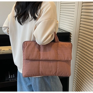 Quilted tote bag in matte brick red shown held by a model in a cozy library setting