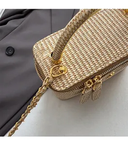 Detailed macro view of the light gold metal zipper and chain hooks on a woven box bag