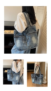 Detail of vintage washed blue denim tote bag featuring dual front zipper pockets