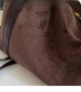 Gros plan sur la texture du daim marron foncé et les coutures en cuir d'un sac cabas
