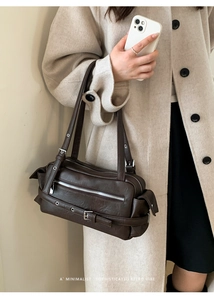 Detail of dark brown retro pillow bag with silver zipper and decorative buckle belt