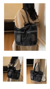 Close-up of black washed denim tote bag with dual front zipper pockets and wide shoulder strap