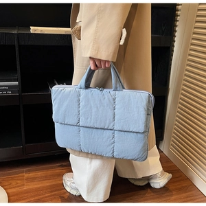 Close-up of light blue quilted nylon tote bag with puffer texture and dual handles