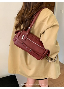 Close-up of burgundy retro shoulder bag with silver zippers and buckle details
