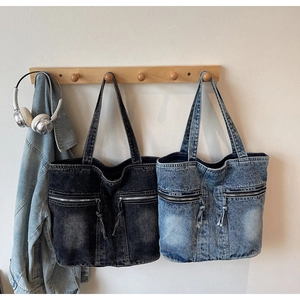 Detail of blue and grey washed denim tote bags with dual front zippers and braided pulls