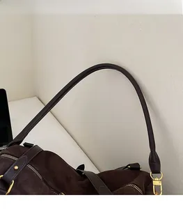 Détail du sac bandoulière en daim marron foncé avec rivets dorés et fermeture à glissière