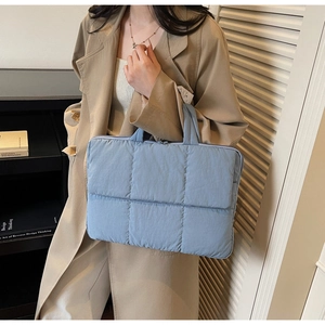 Close-up of quilted light blue laptop bag with top zipper and soft padded fabric texture