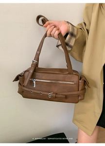 Detail of a brown faux leather shoulder bag featuring silver buckle and zip accents