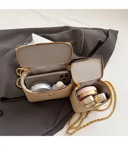 Detail view of woven straw handbags in two sizes with gold chain and quilted lining
