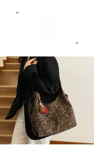 Spacious leopard print tote bag with plush pom-pom accessory worn on a female shoulder