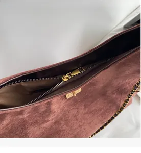 Macro detail of smooth zipper and gold hardware on red suede shoulder bag