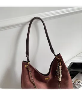 Detailed close-up of dark wine red suede tote bag with golden chain and bead charm