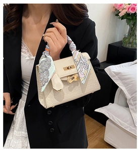 Detail of cream crocodile embossed Kelly bag with silk scarf handle and metal clasp
