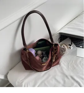 Detail of spacious brown suede shoulder bag with gold chain and interior storage capacity
