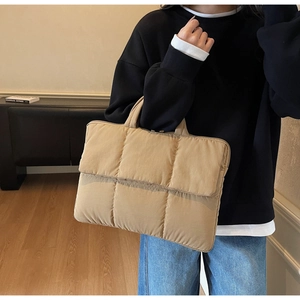 Detail of khaki quilted laptop tote bag showing puffy texture and soft carry handles