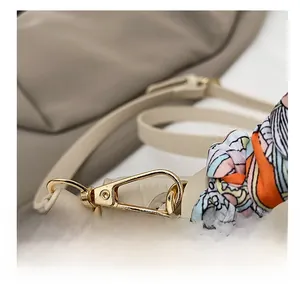 Detail of cream crocodile pattern leather bag with gold buckle and colorful silk scarf