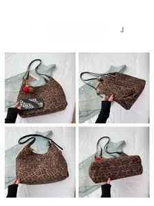 Detail view of leopard print tote bag with plush pompom charms and reinforced bottom panel