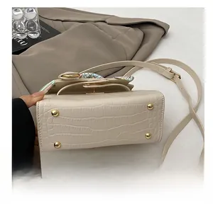 Detail of wear-resistant gold metal feet on beige crocodile embossed leather handbag