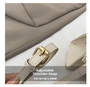 Detail of adjustable leather shoulder strap with gold metal buckle on beige crossbody bag