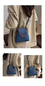 Detail of retro denim doctor bag showing blue fabric texture and brown circular handle