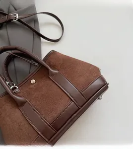 Detail of vintage suede crossbody bag with brown leather stitching and gold hardware