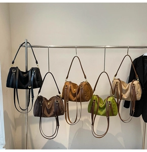 Vue détaillée de cinq couleurs de sacs à bandoulière en suède sur un support en métal
